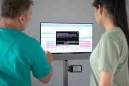 Terapeut analizand alaturi de pacienta rezultatele unui test de echilibru pe un monitor conectat la un sistem digital de evaluare