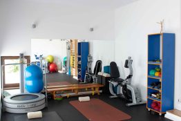 Vedere de ansamblu asupra salii de recuperare medicala, cu bicicleta, saltele, mingi de gimnastica, trambulina si rafturi cu echipamente de kinetoterapie