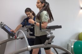 kinetoterapeut monitorizand o pacienta in timpul unui exercitiu de reeducarea mersului pe banda de alergare intr-o sala de recuperare medicala
